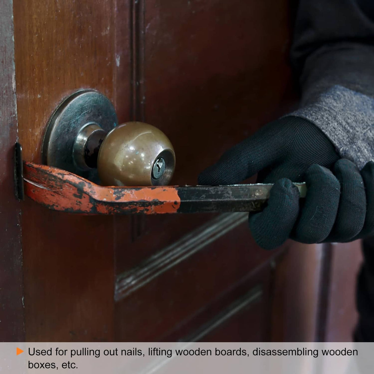 Nail puller claw pry bar held by a glove, prying near a wooden door panel