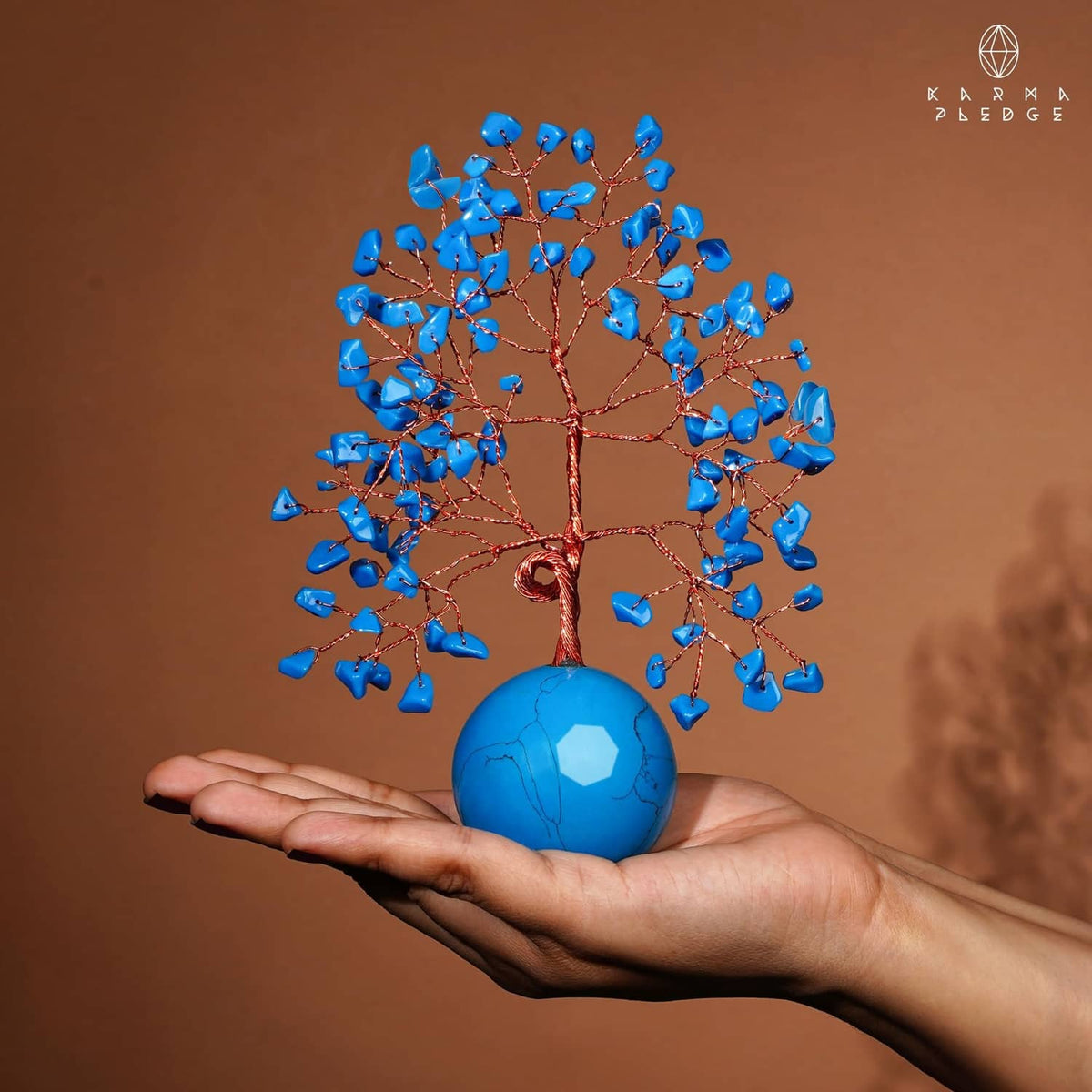 Turquoise ball base Tree of Life ornament held in hand, with blue crystal leaves
