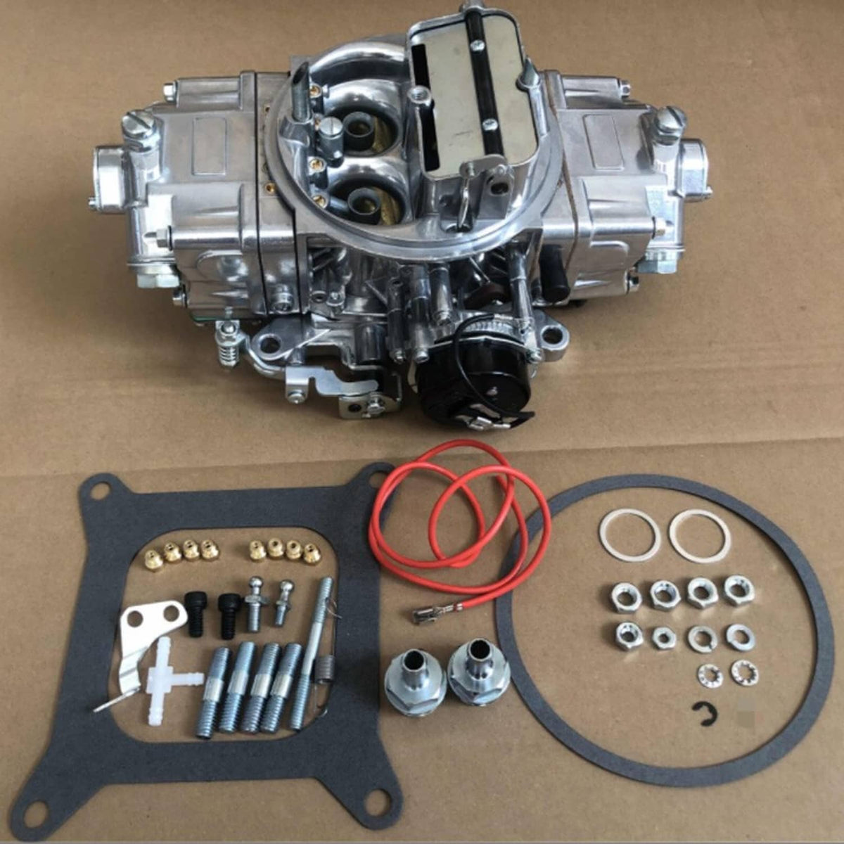 4-barrel carburetor with disassembled kit parts and gaskets laid out on board