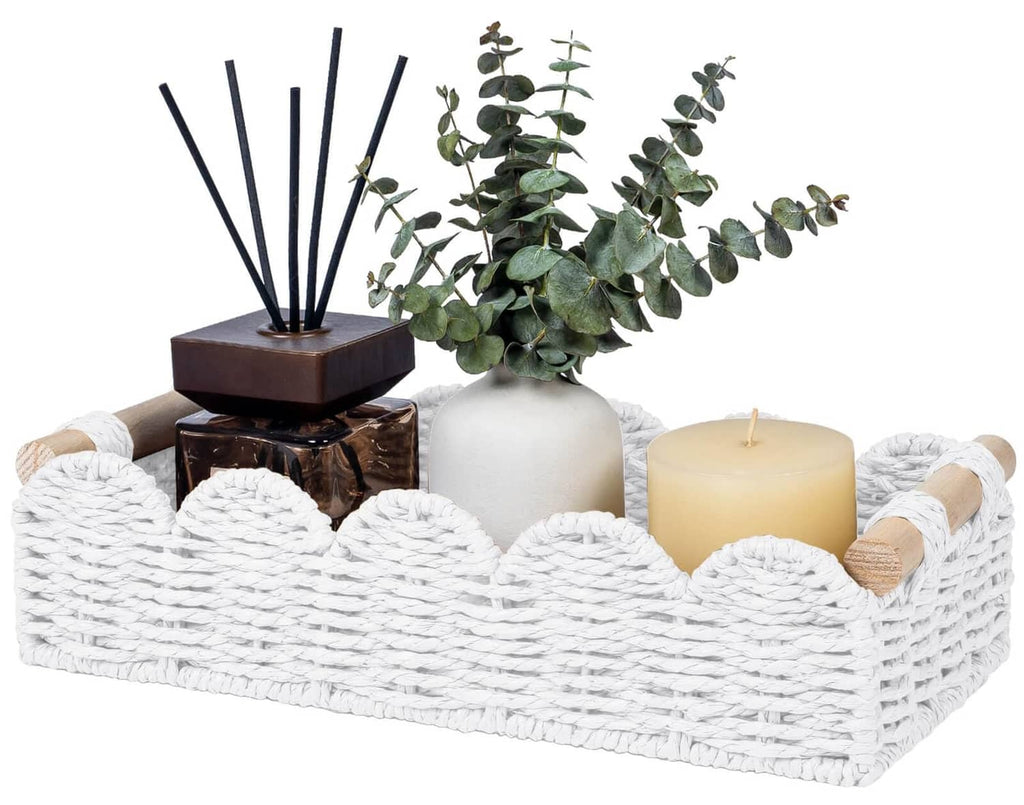 White woven toilet paper storage basket with rope handles, holding candles and decor