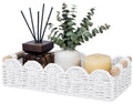 White woven toilet paper storage basket with rope handles, holding candles and decor