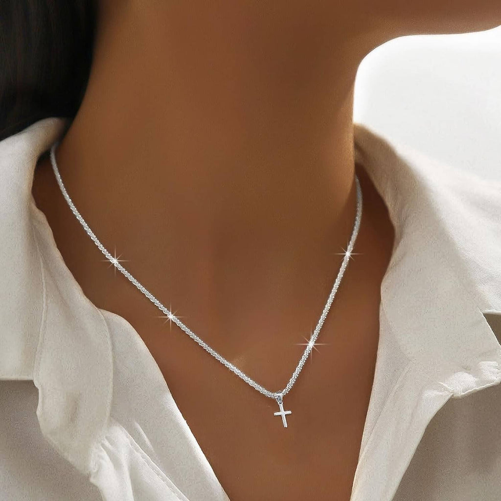Silver-tone layered necklace with cross charm pendant against a light V-neck top
