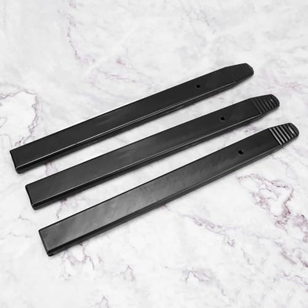 Three black long pry bar rim protectors laid out, each with ridged end and hole