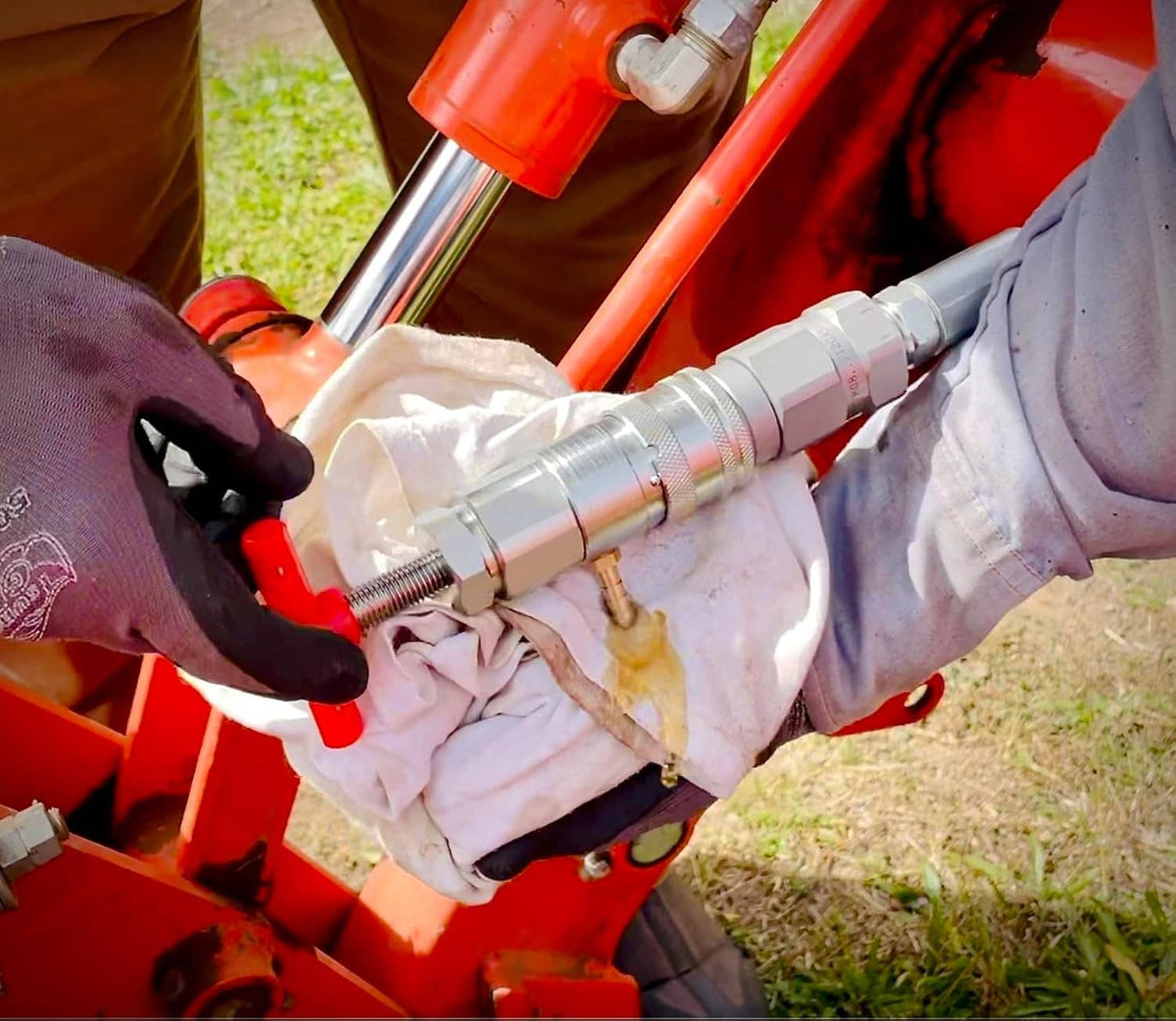 Hydraulic quick coupling connected on equipment with gloved hands and hoses