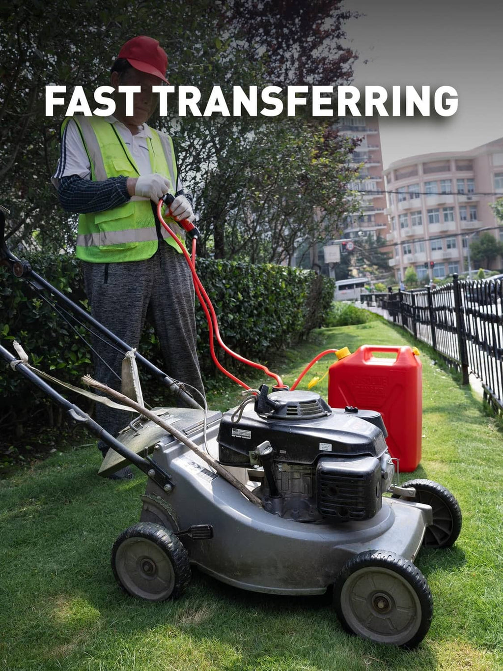 Red transfer pump connected to a fuel container beside a lawn mower