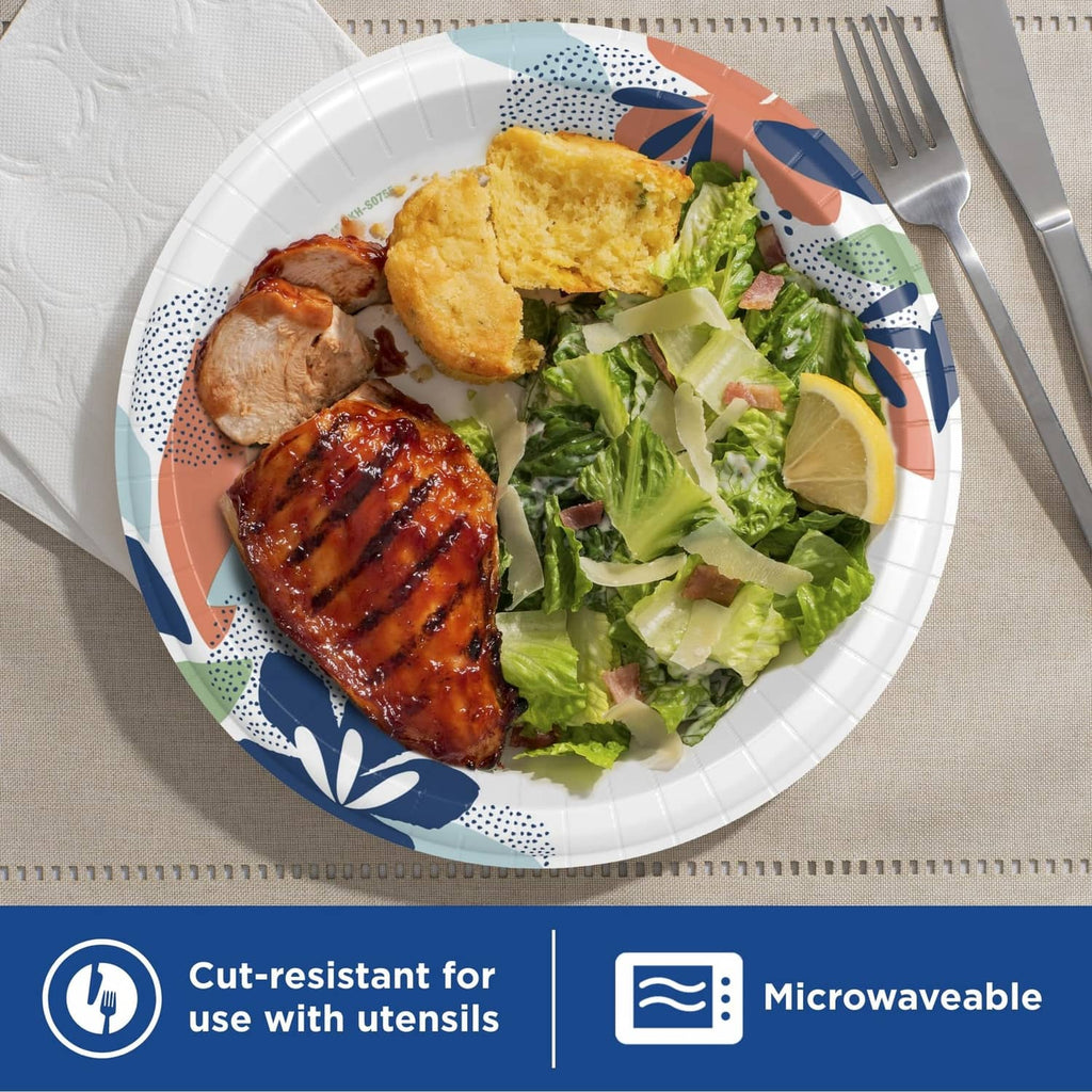 White paper plate with colorful rim pattern serving grilled chicken, bread, and salad