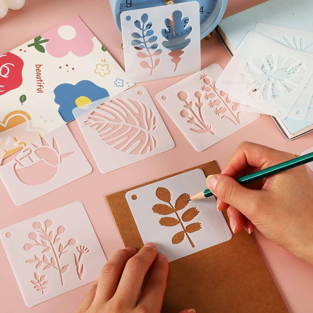 Unpainted flower and leaf stencils with a marker being used on one sheet