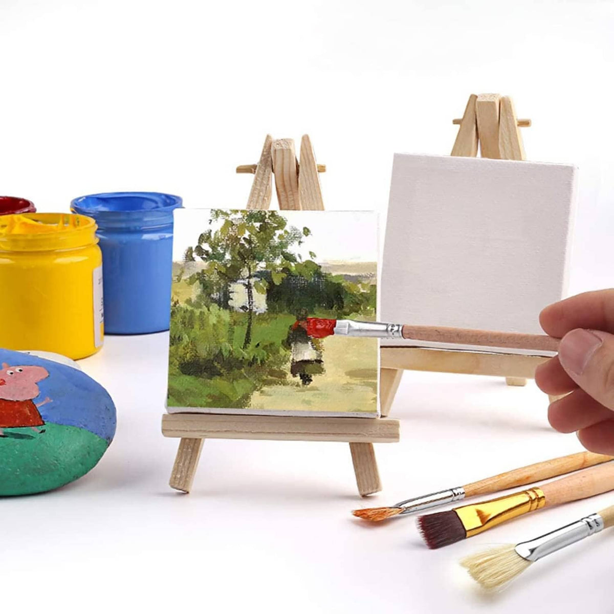 Mini canvases on wooden easels with paintbrushes and small paint jars