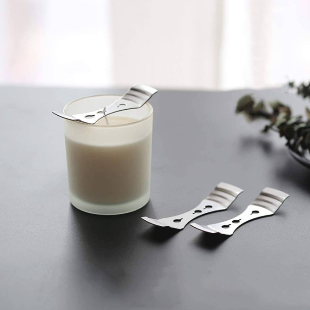 Silver wick centering clips beside a jar candle, U-shaped metal ring design