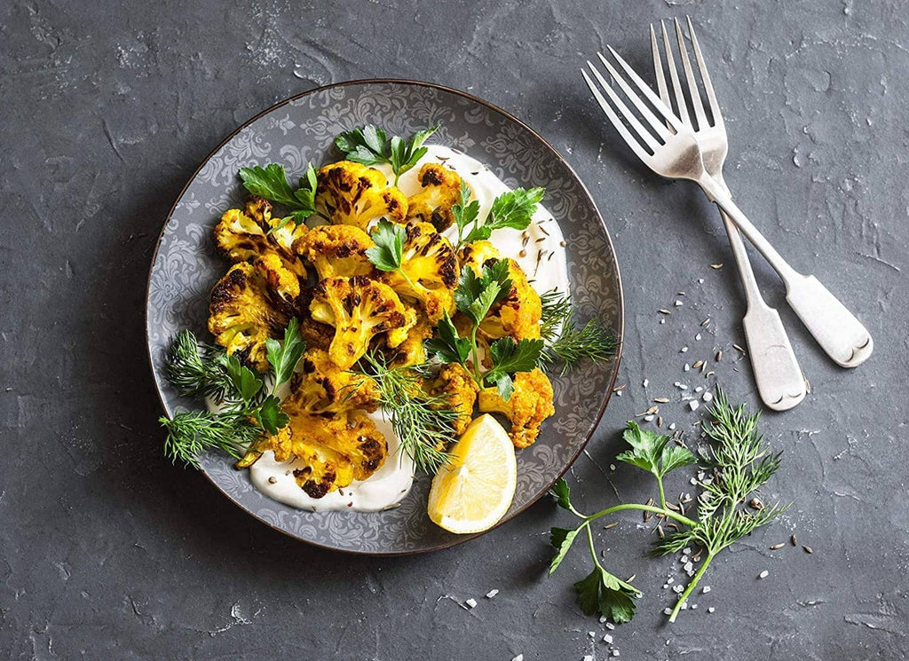 Turmeric-seasoned roasted dish on a plate with lemon wedge and herbs