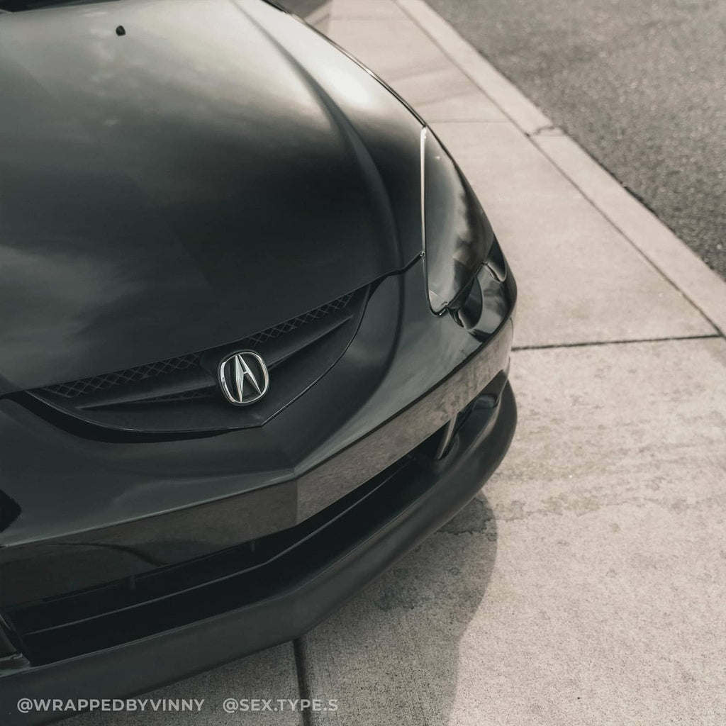 Black high-gloss vinyl-wrapped car front hood and grille area, realistic paint-like finish