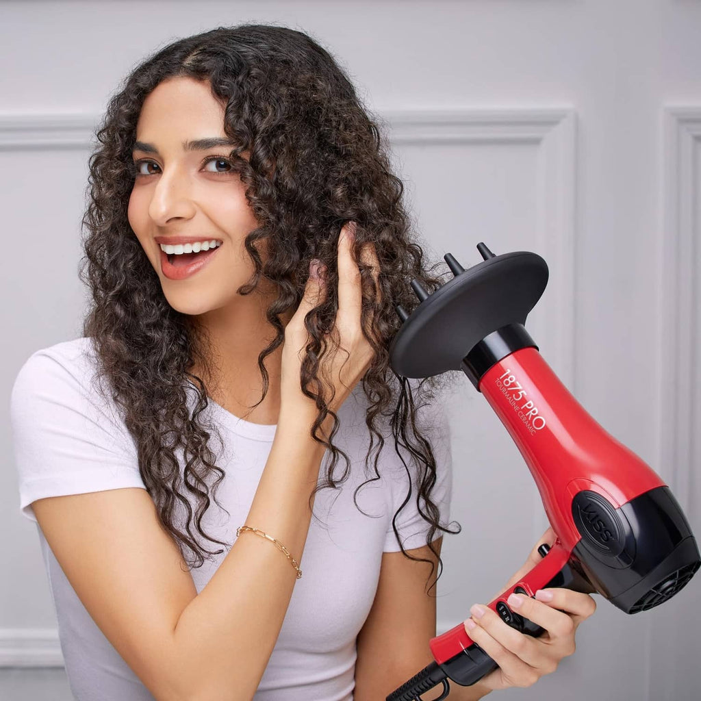 Red and black hair dryer in hand beside a smiling woman drying curly hair
