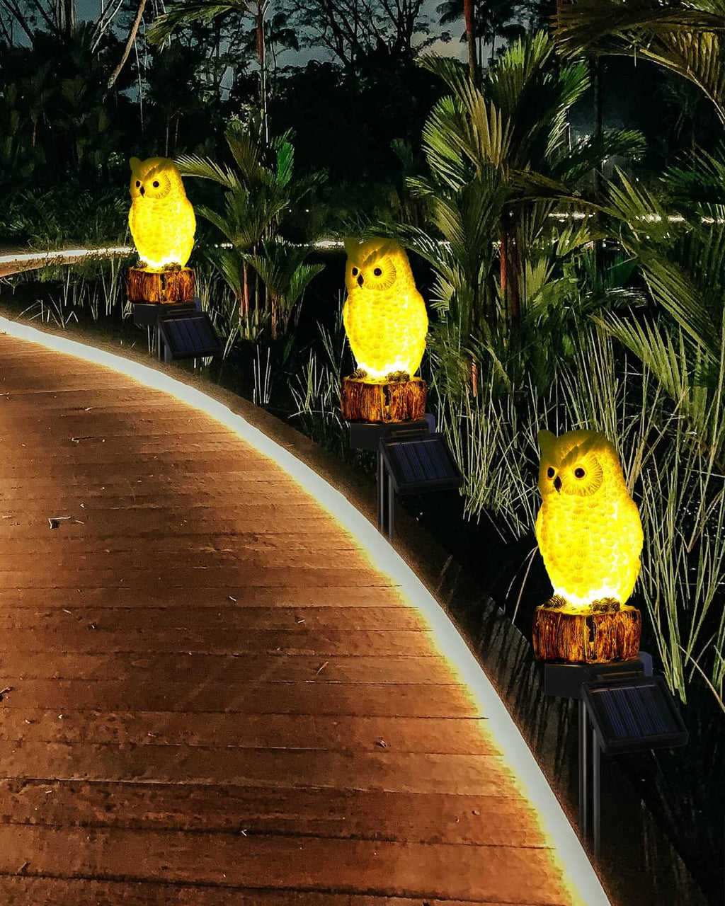Glowing yellow owl solar garden stake lights with log bases along walkway