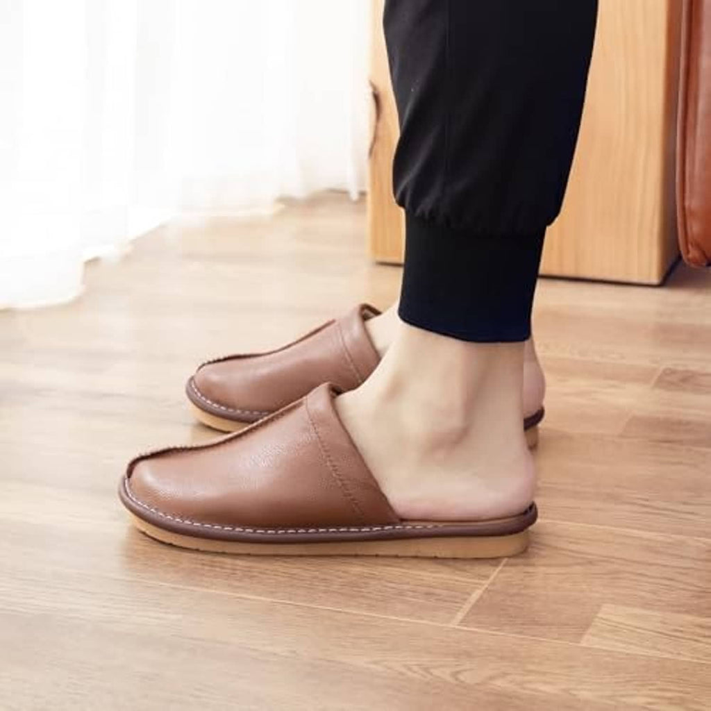 Pair of light brown leather slide slippers worn with dark pants
