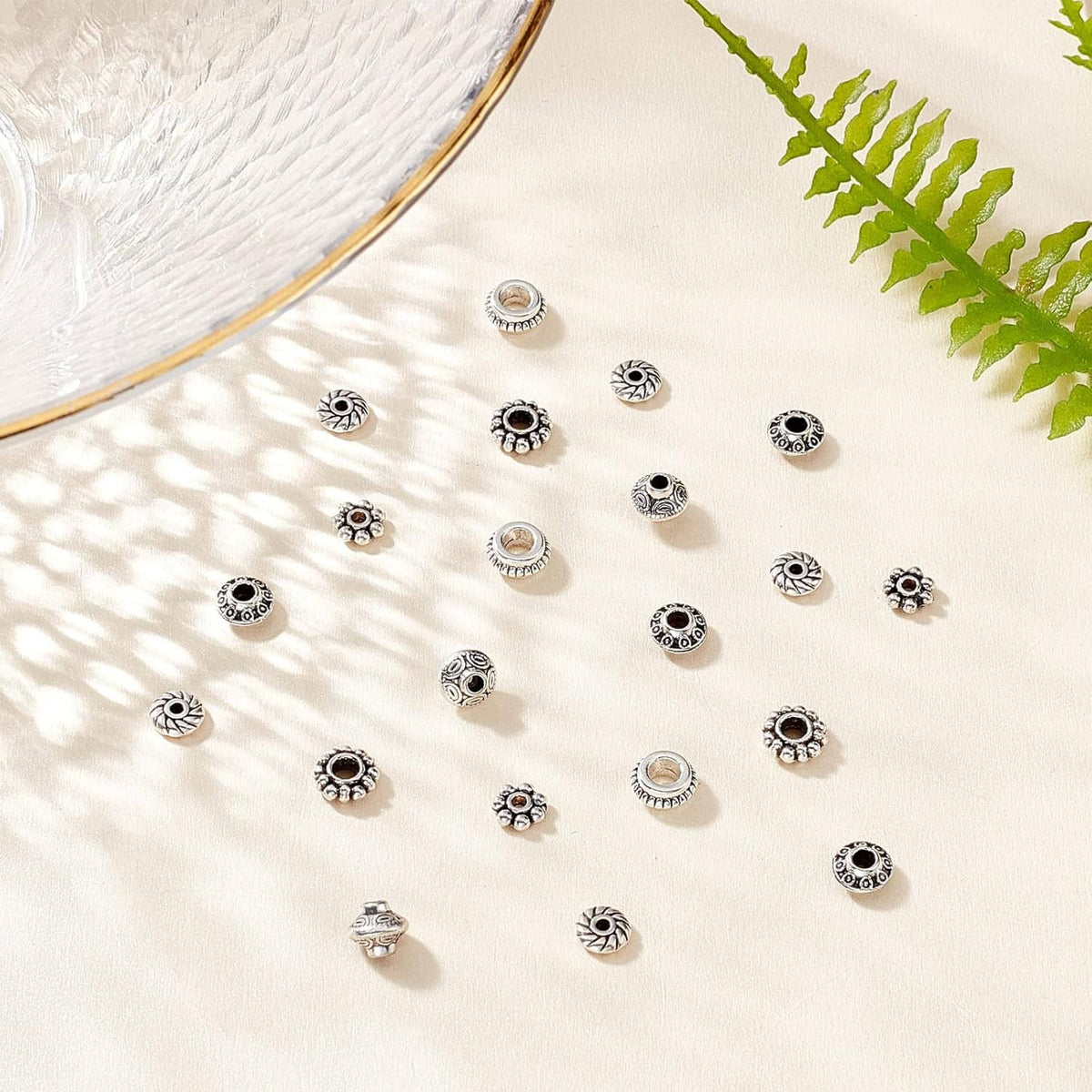 Loose antique silver spacer beads arranged on a light surface, round textured bead caps