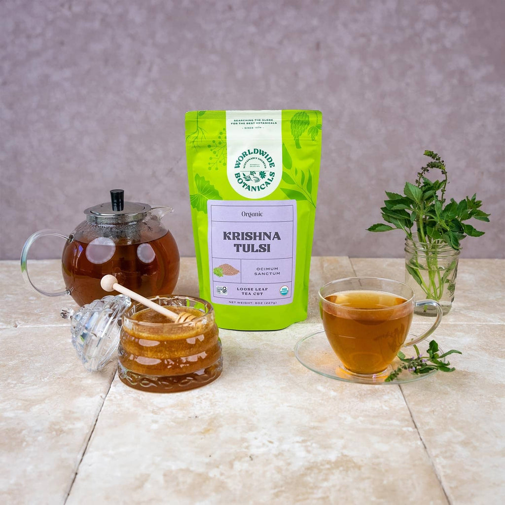 Krishna Tulsi tea pouch with brewed cup and fresh basil sprigs
