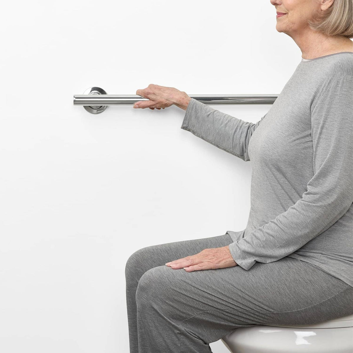 Person using a wall-mounted stainless steel shower grab bar for support