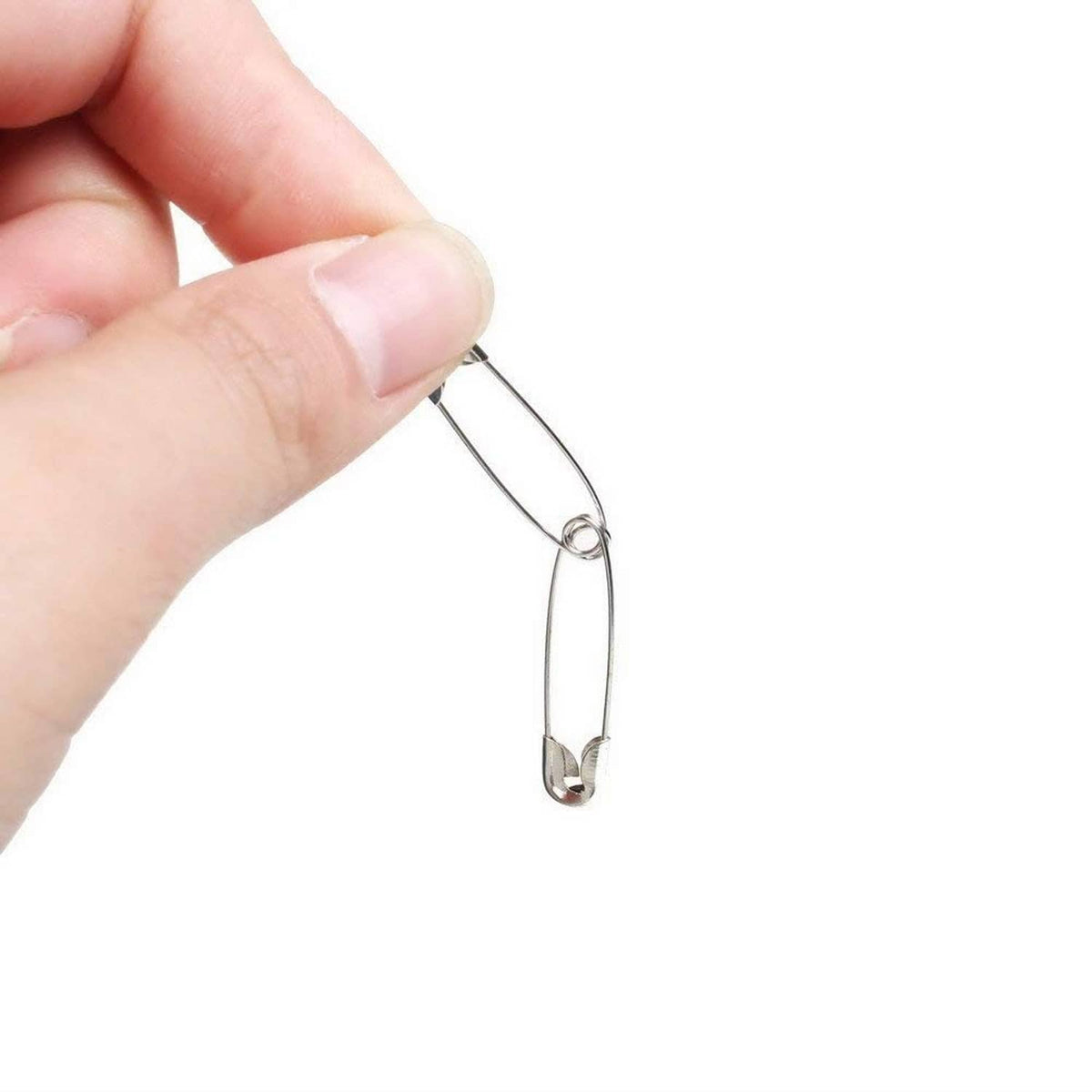 Safety pin held in hand, silver-tone metal clasp