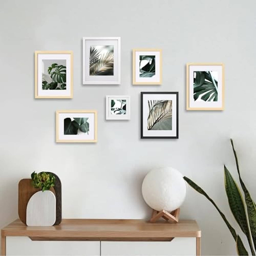 Gallery wall with multiple small photo frames in black, white, and light wood finishes