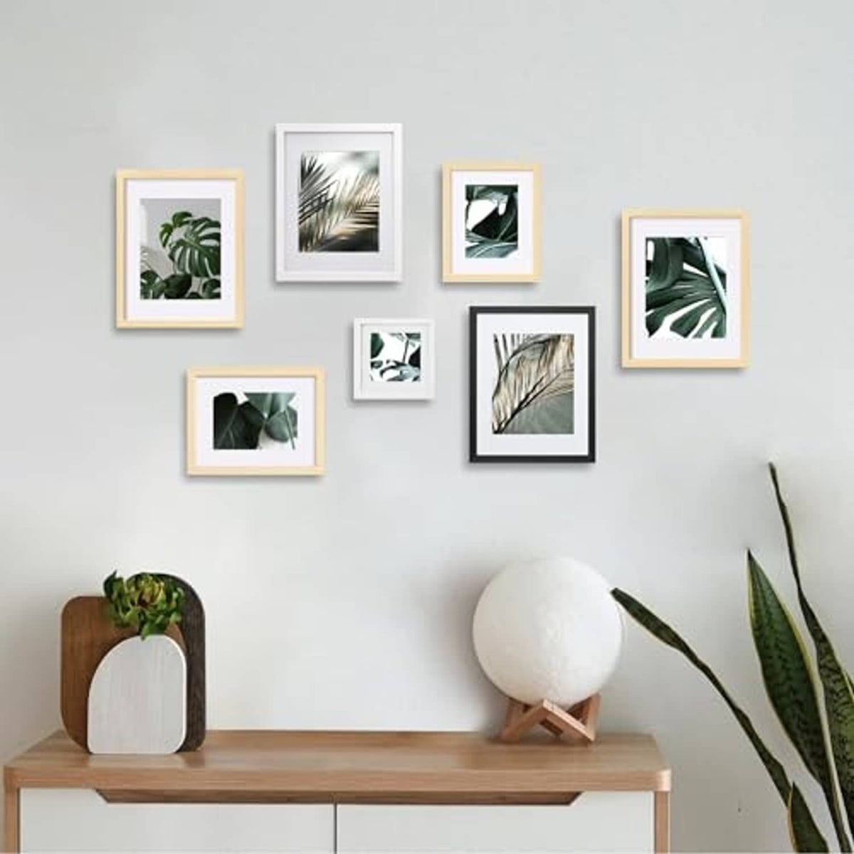 Gallery wall with multiple small photo frames in black, white, and light wood finishes