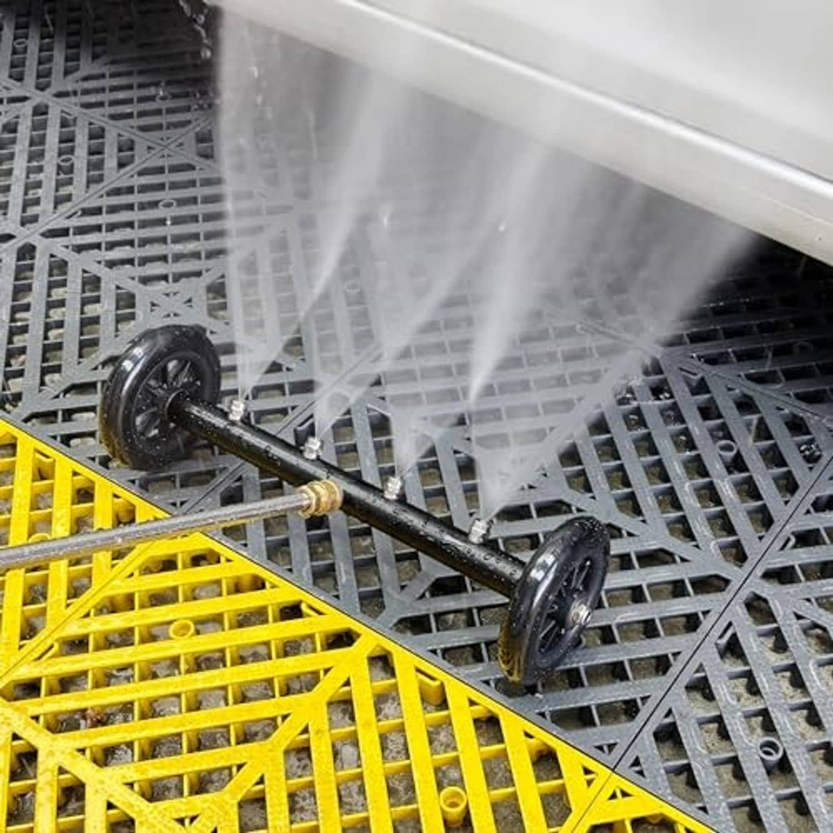 Undercarriage cleaner with spray stream aimed under vehicle on a metal platform