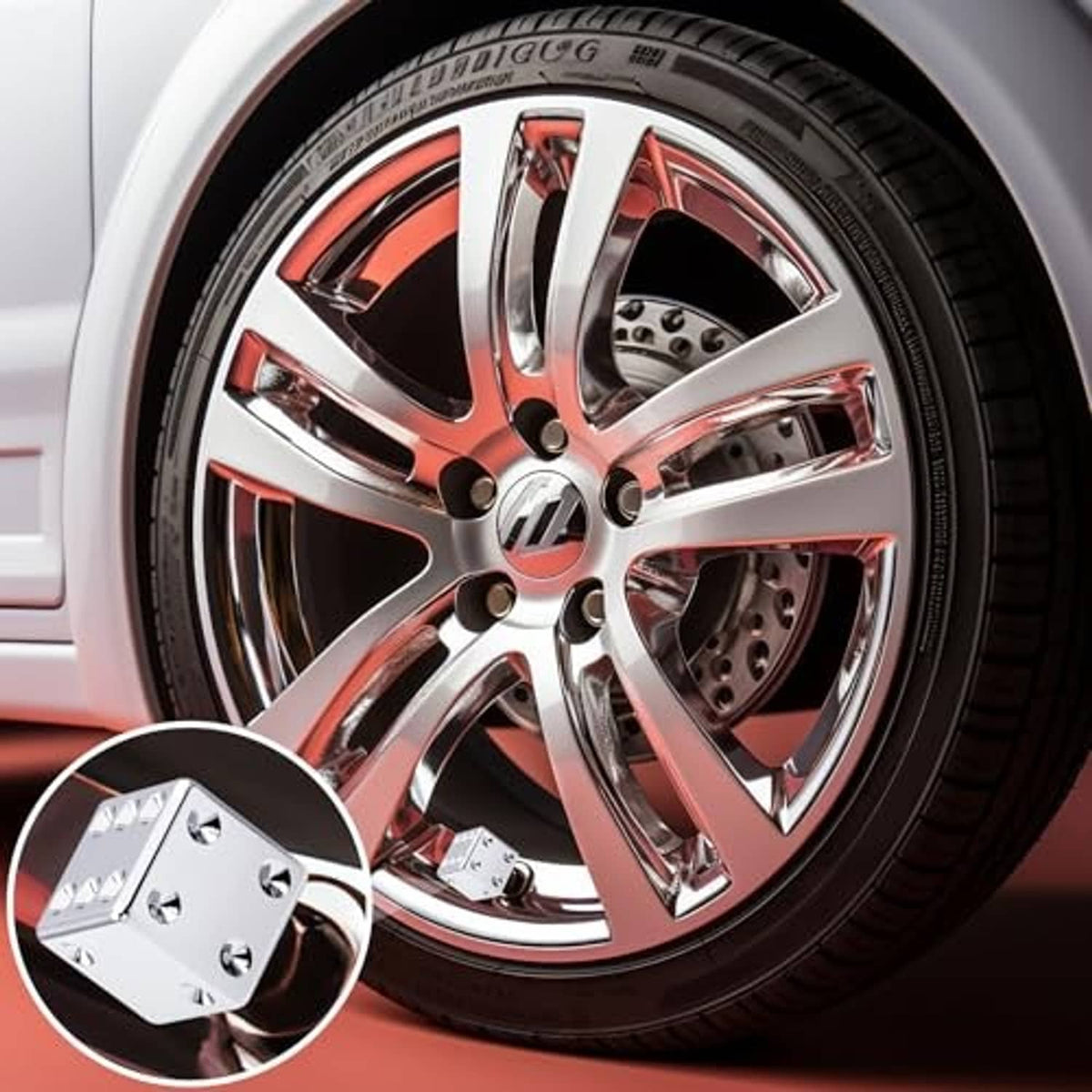 Dice-shaped chrome tire valve stem cap on wheel valve, with gold threaded insert