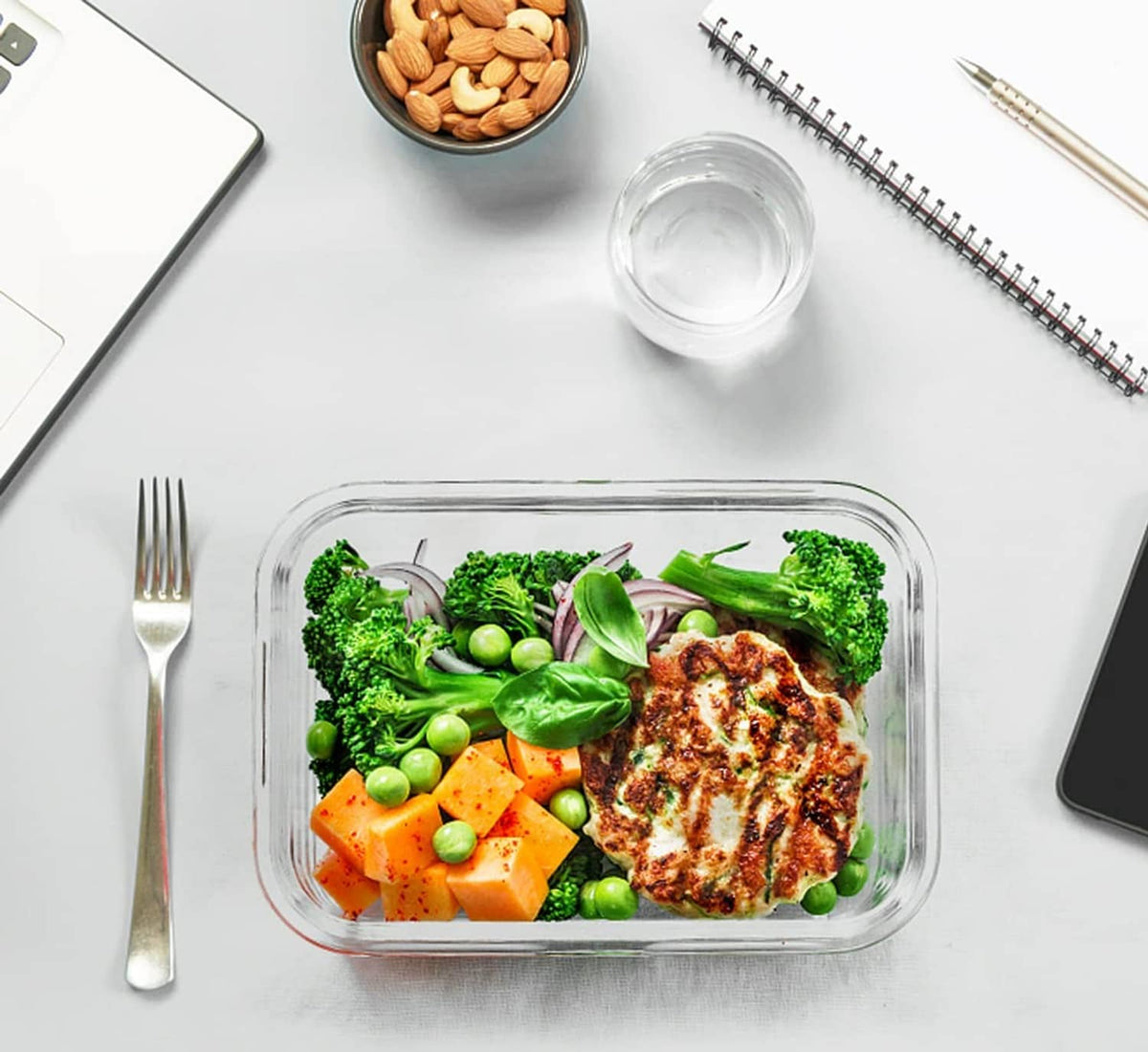 Rectangular glass food storage container with gray snap lid holding prepared meal