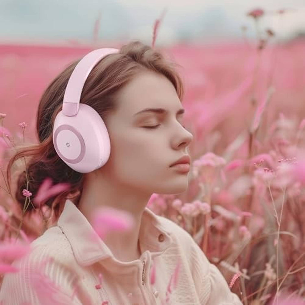 Pink wireless over-ear headphones worn by a woman, head turned to the side
