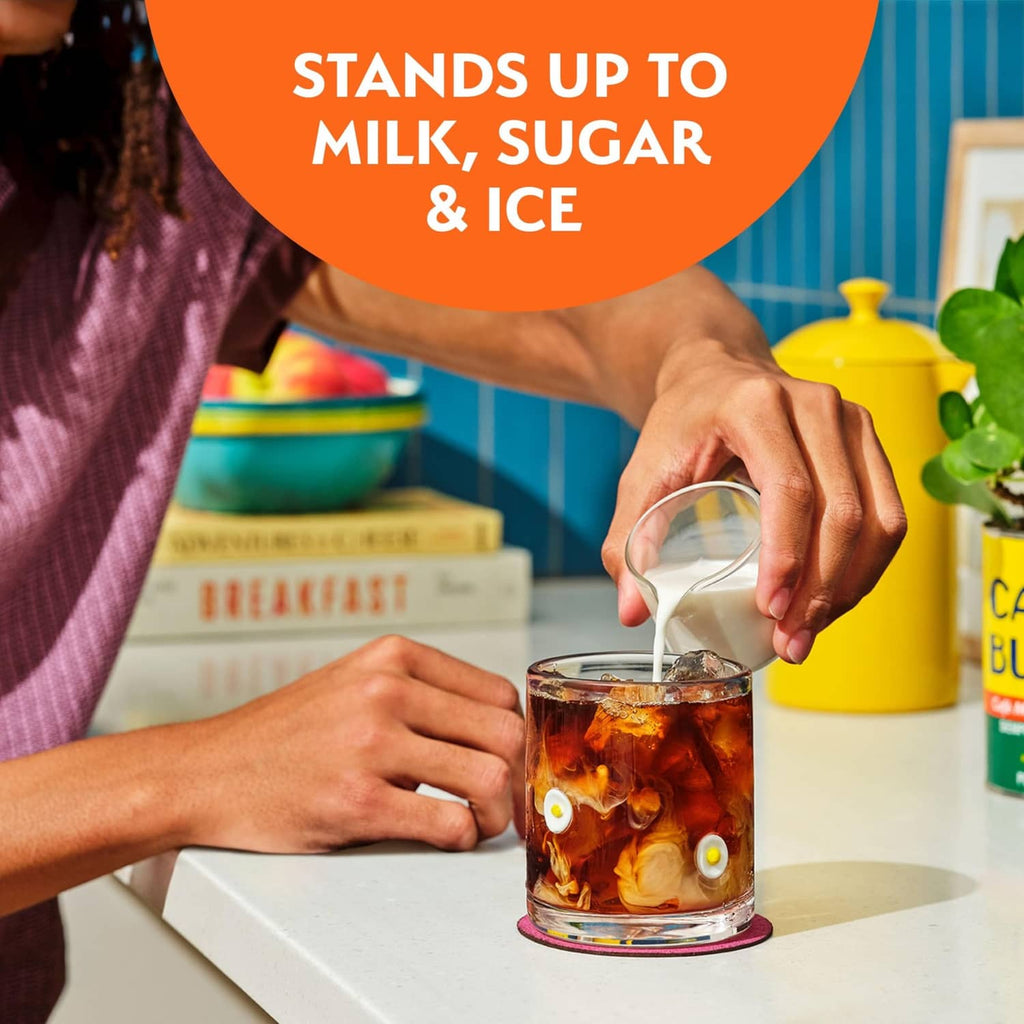 Glass of iced coffee with hands pouring coffee over ice