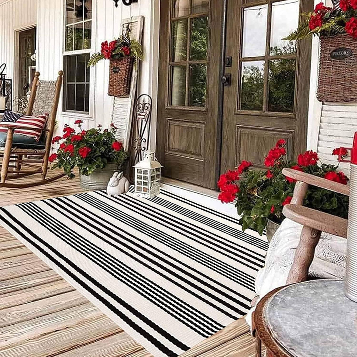 Black-and-white striped outdoor rug laid on a wood deck, rectangular with horizontal bands.