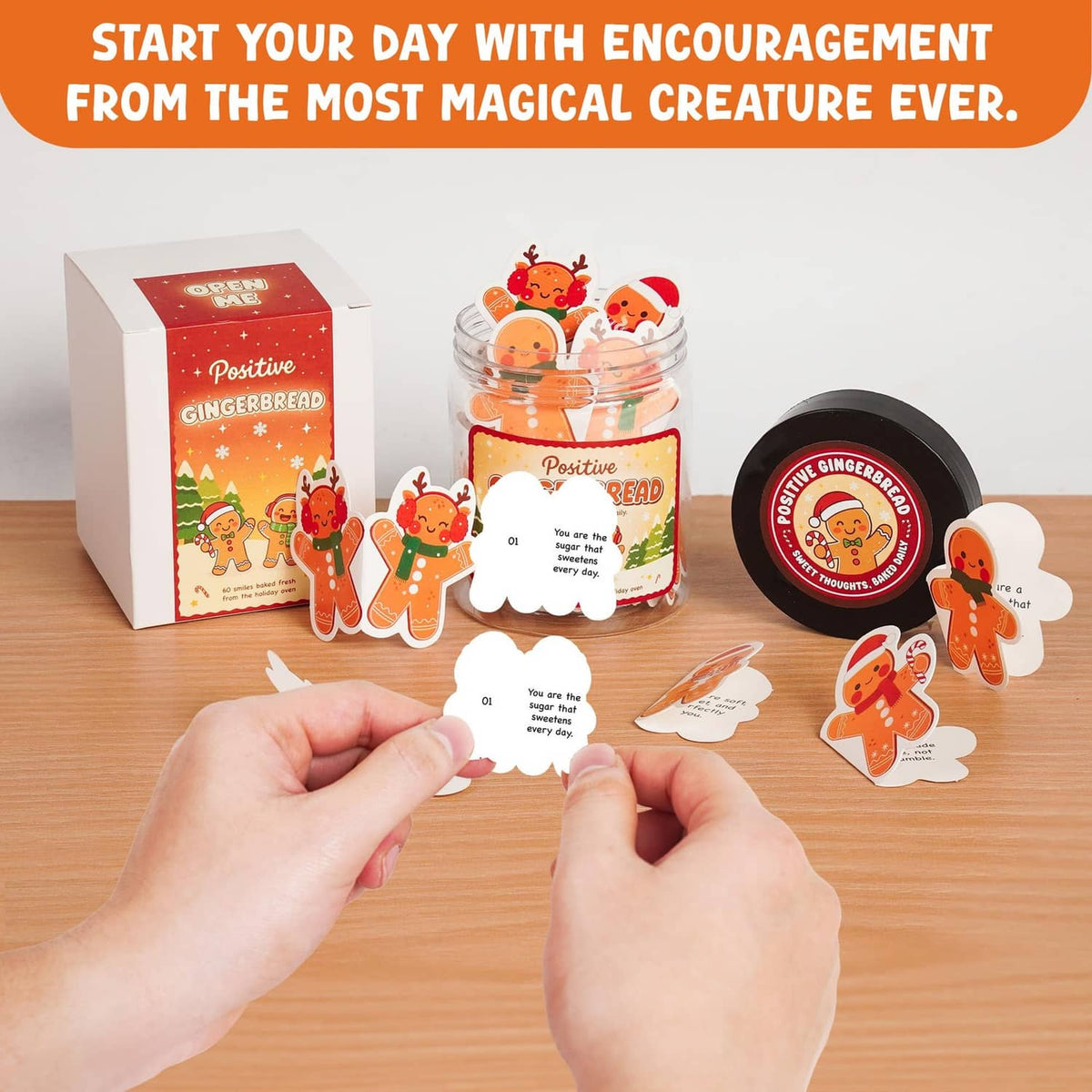 Gingerbread affirmation jar with black lid, held near greeting cards and gingerbread cutout notes
