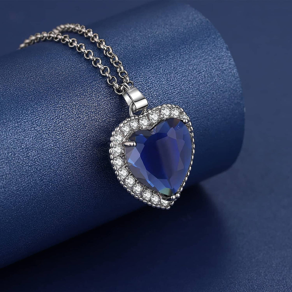 Silver-tone heart pendant necklace close-up with dark blue faceted center stone