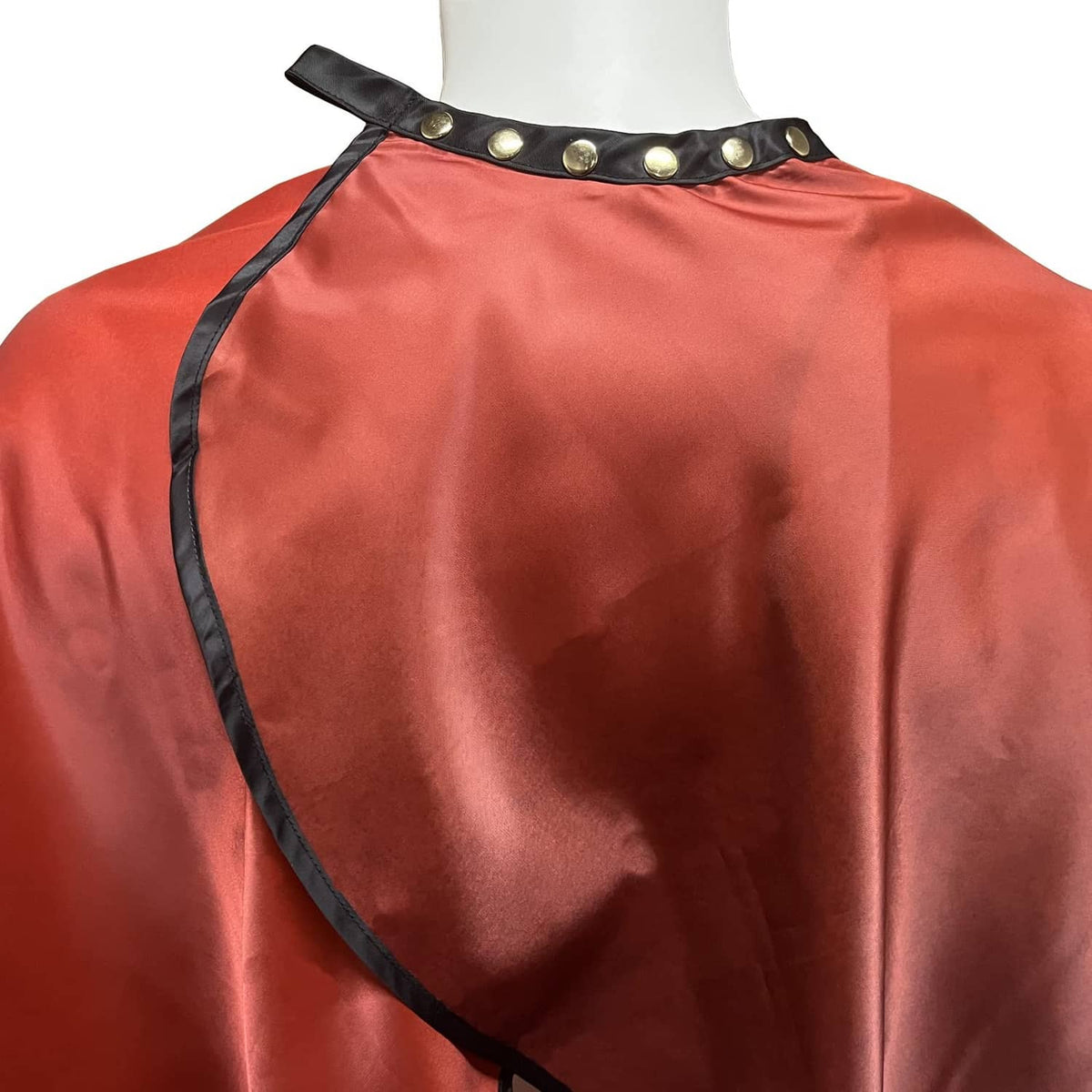 Red barber cape with black neck trim and snap closure straps