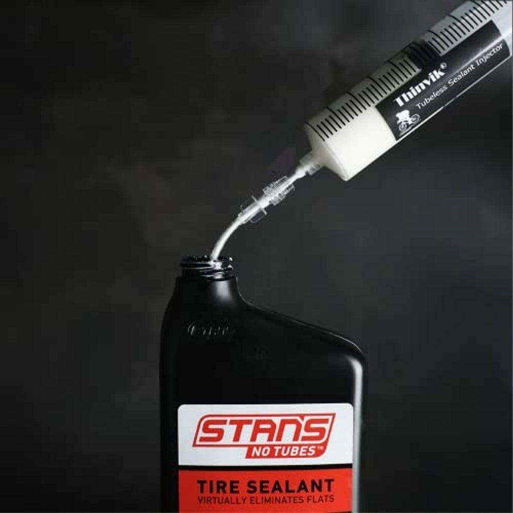 Sealant injector syringe dispensing sealant into a Stans No Tubes Tire Sealant bottle