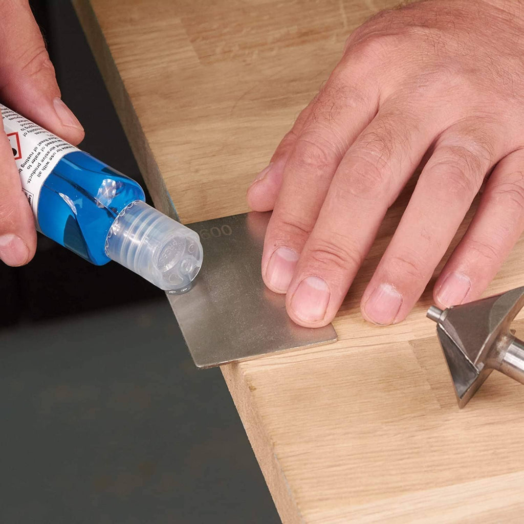 Blue abrasive lapping fluid dispensed onto metal tool on a wooden workbench