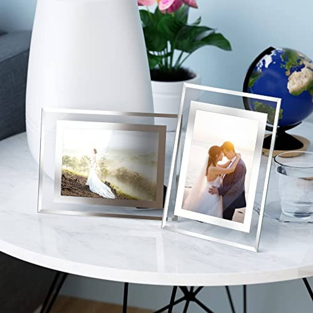 Set of white 5x7 glass photo frames leaning on tabletop with two photos