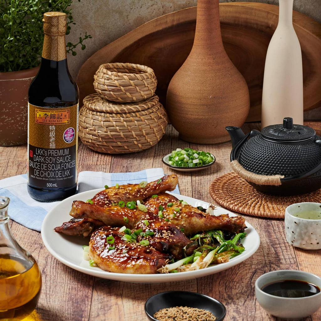 Lee Kum Kee premium dark soy sauce bottle on table with plated chicken and bok choy
