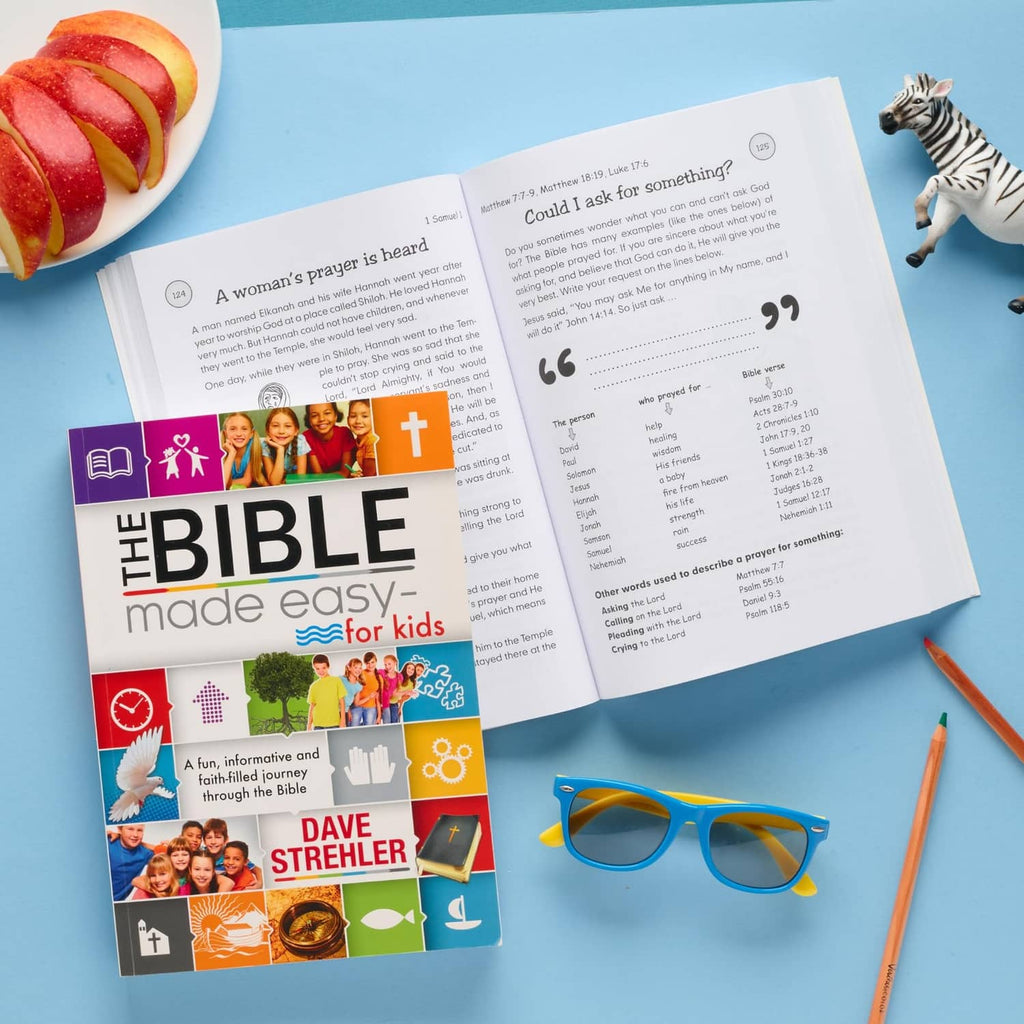 Kids Bible book open to printed passages, with cover booklet and reading glasses