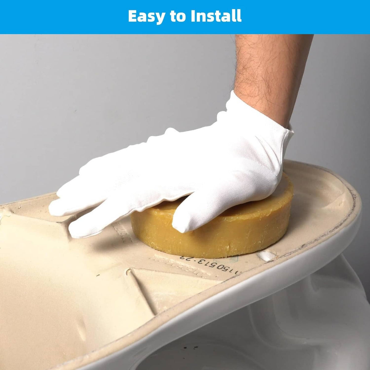 Yellow toilet wax ring gasket pressed onto toilet flange, gloved hand installation