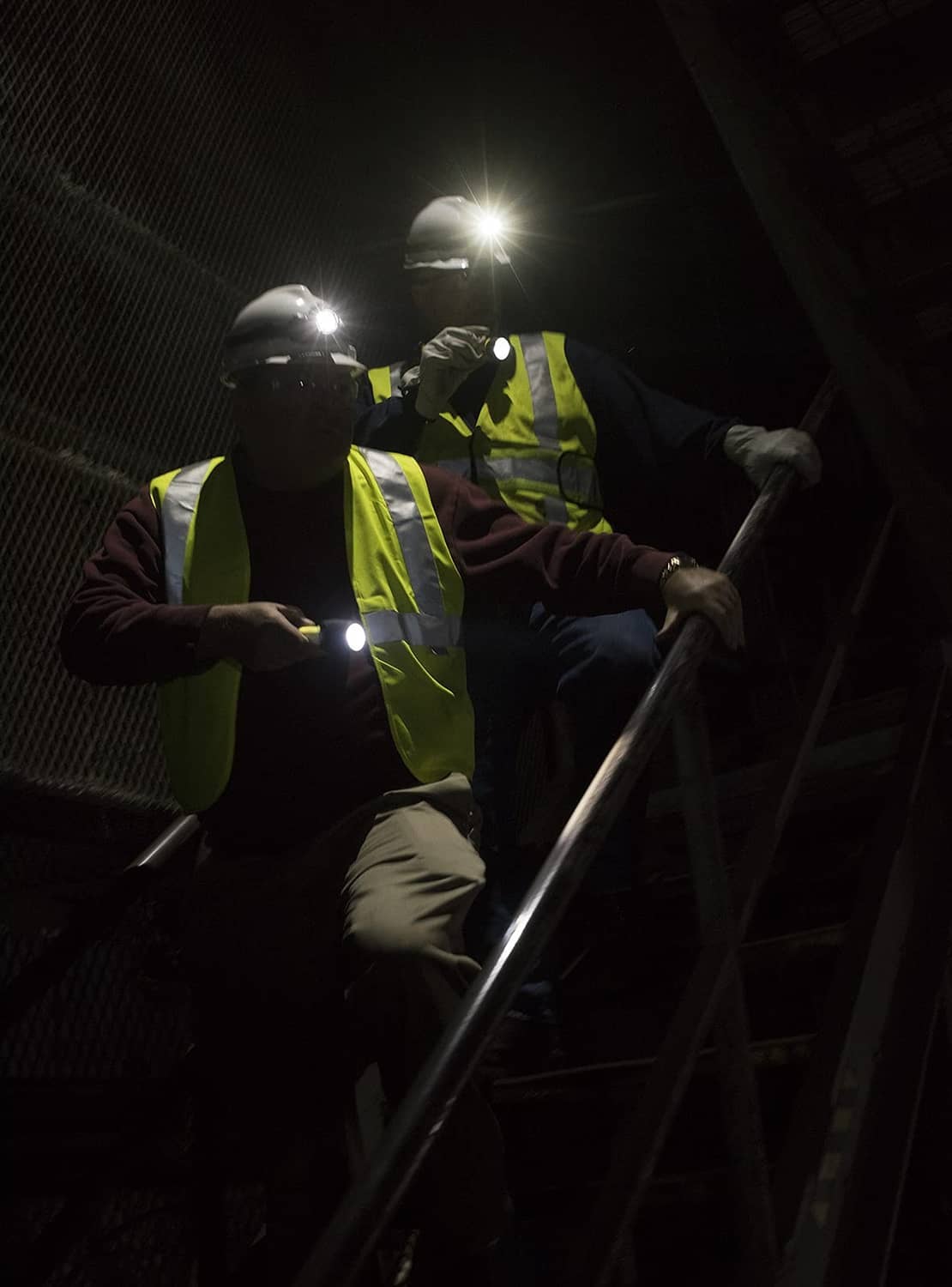 Headlamp on worker’s head with bright white beam and high-visibility vest