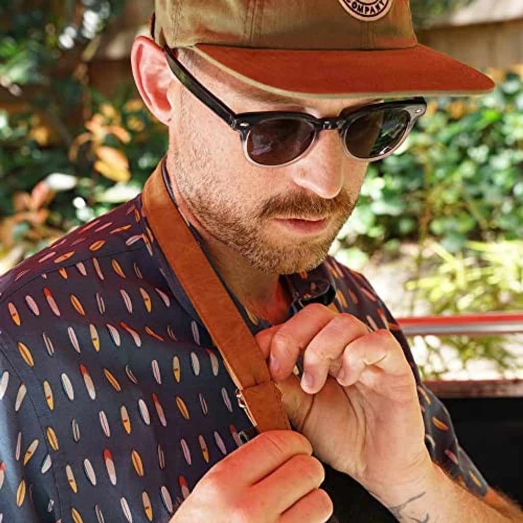 Close-up of tan faux leather apron neck strap on a dark charcoal cooking apron
