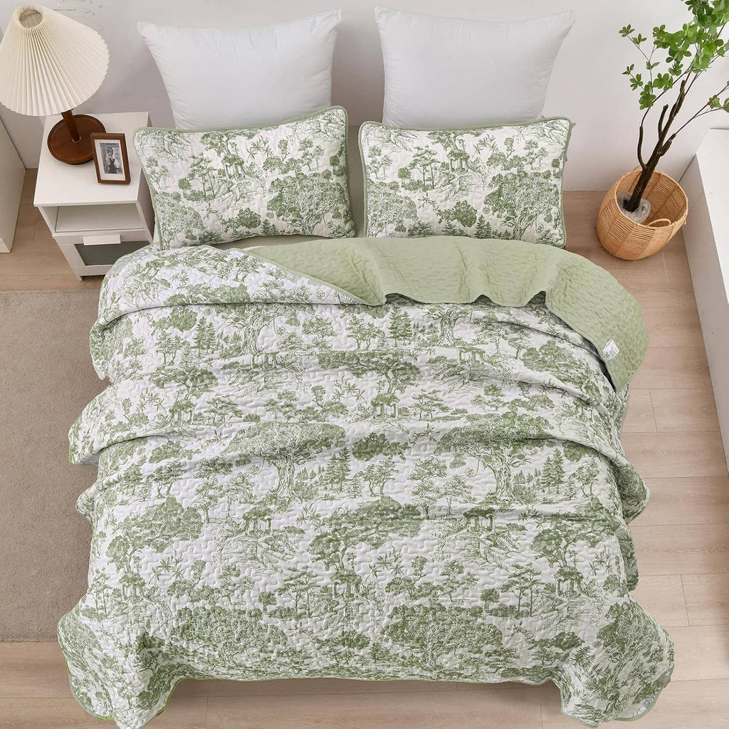 Sage green botanical quilt with two pillow shams, arranged on a queen bed
