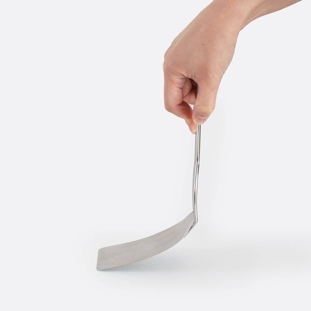 Hand holding a stainless steel cookie spatula with thin flat turner blade