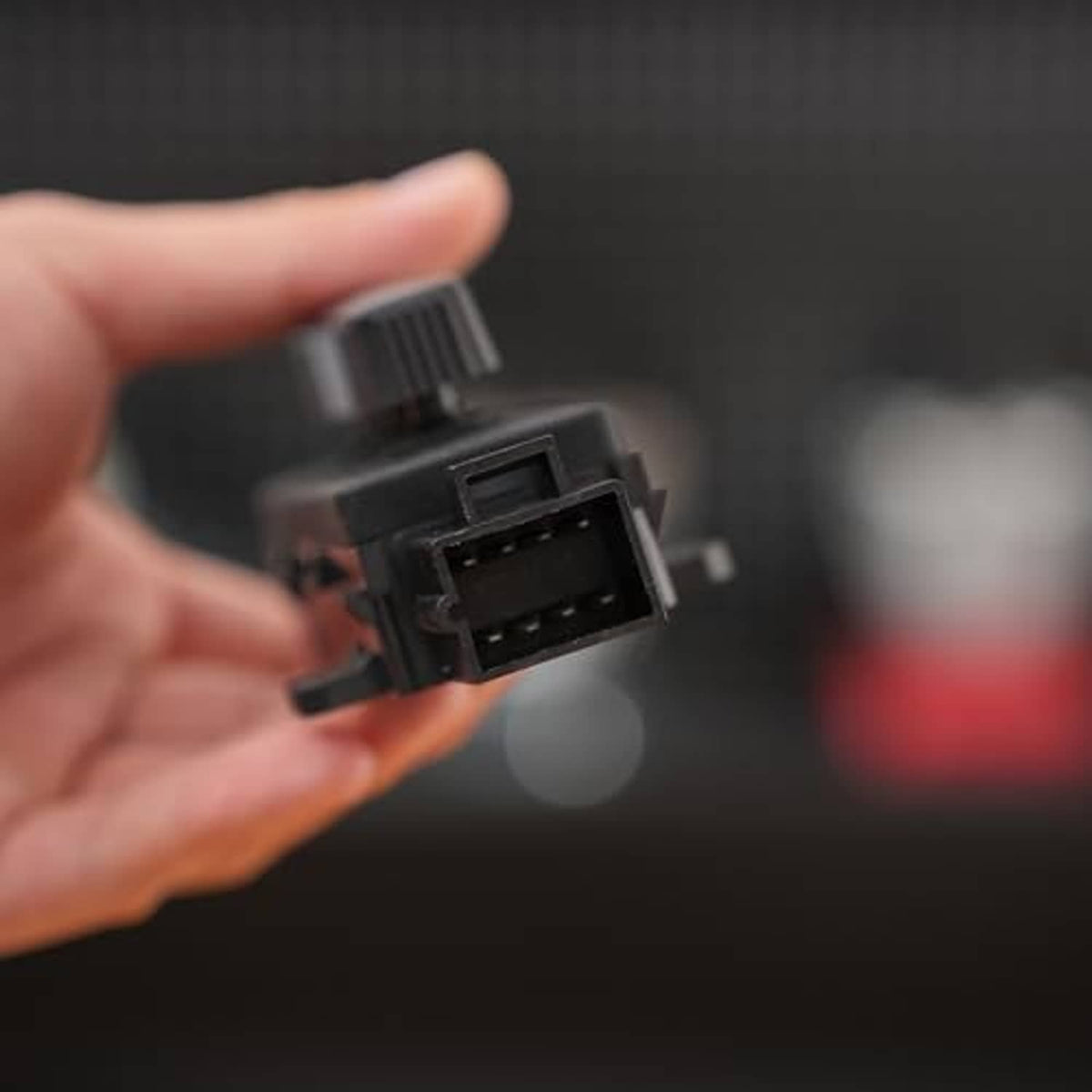 Black power seat switch underside connector facing camera, handheld