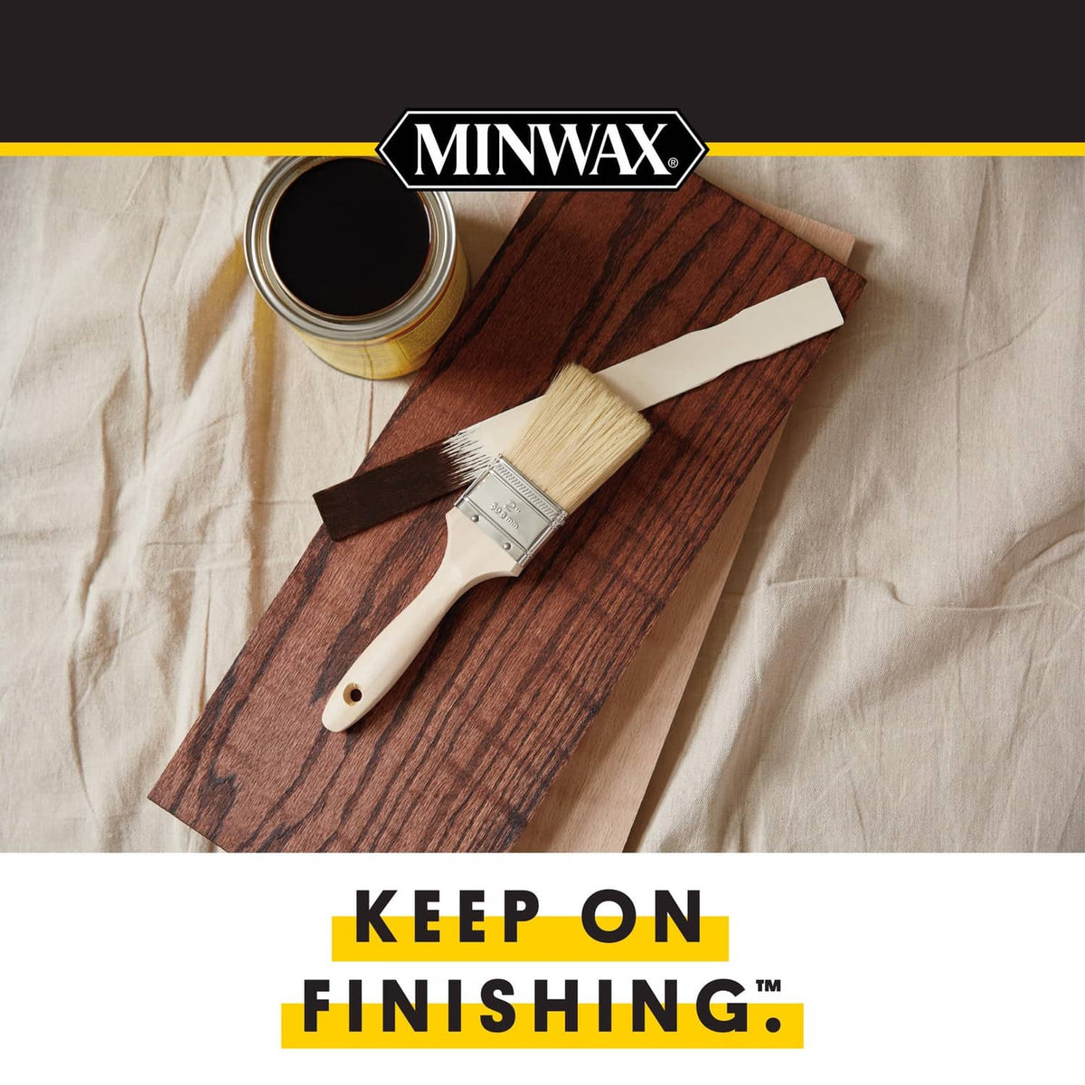 Wood finish swatch with stain bottle and brush on cloth