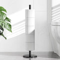 Matte black toilet paper stand with vertical post and round base holding a roll