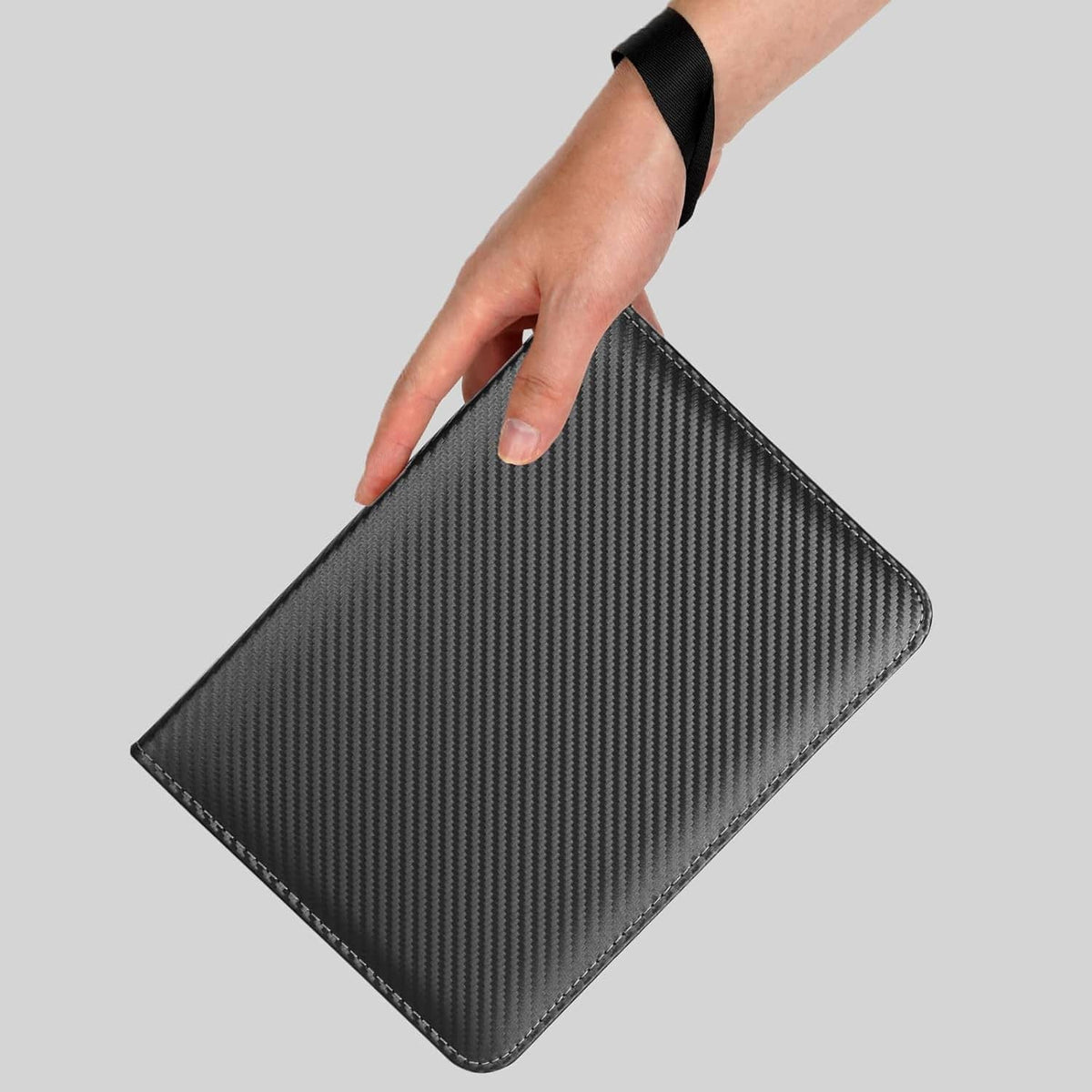 Black zip card binder with carbon-fiber cover, held in hand with wrist strap