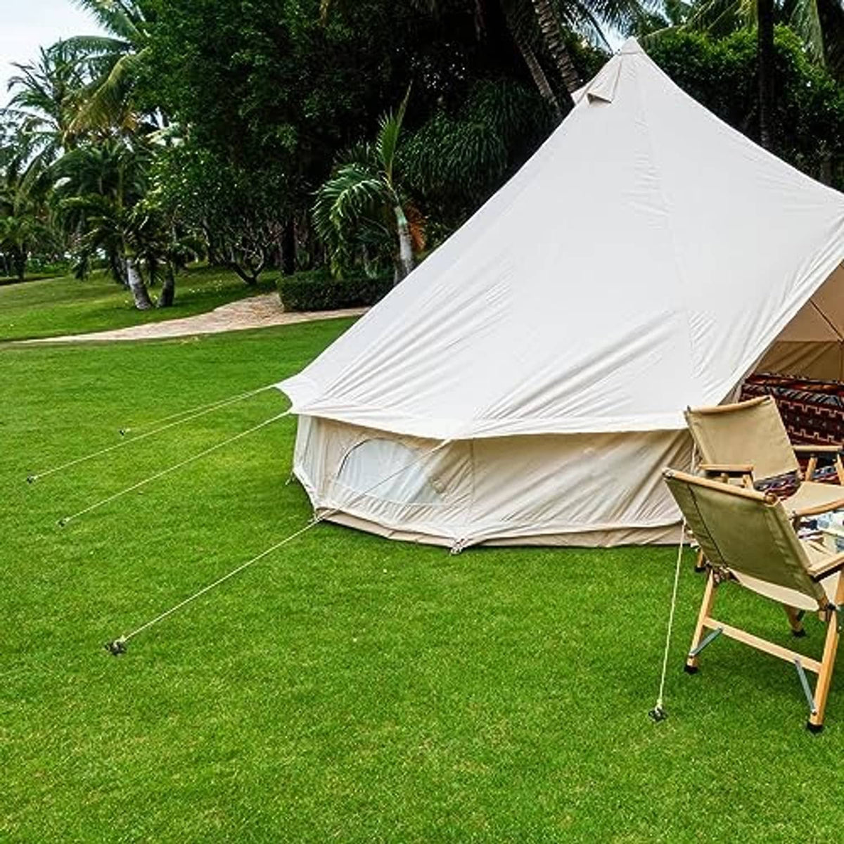 Black tent stakes securing a white canopy tent on grass