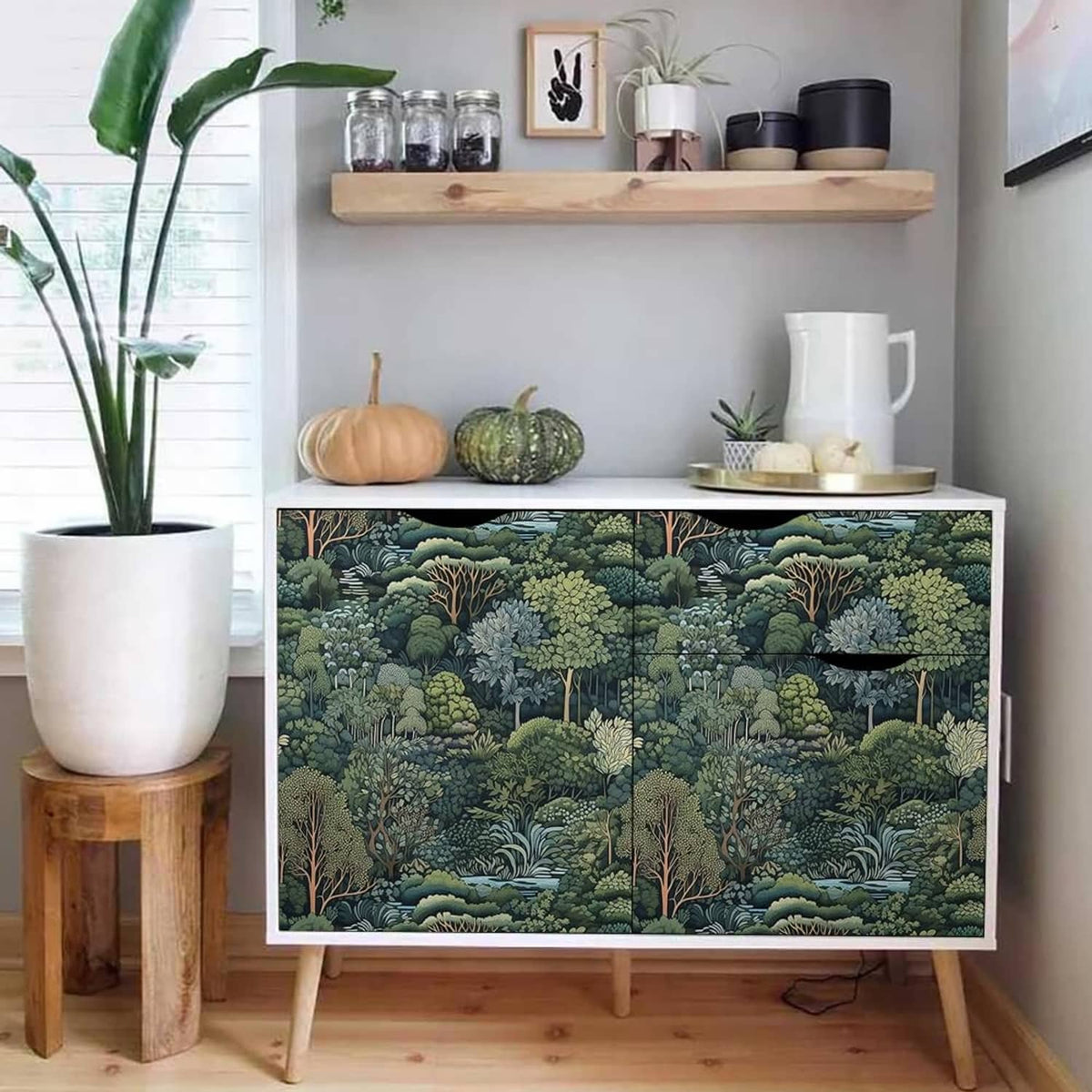 Green forest tree mural wallpaper backing a TV stand with pumpkins and jars on shelves