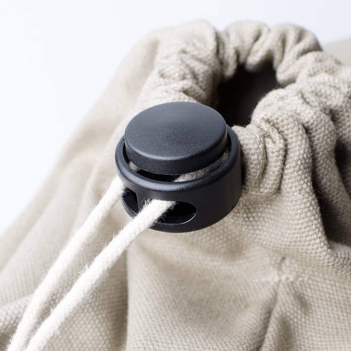 Black cord lock end spring stopper attached to drawstring fabric, screw insert